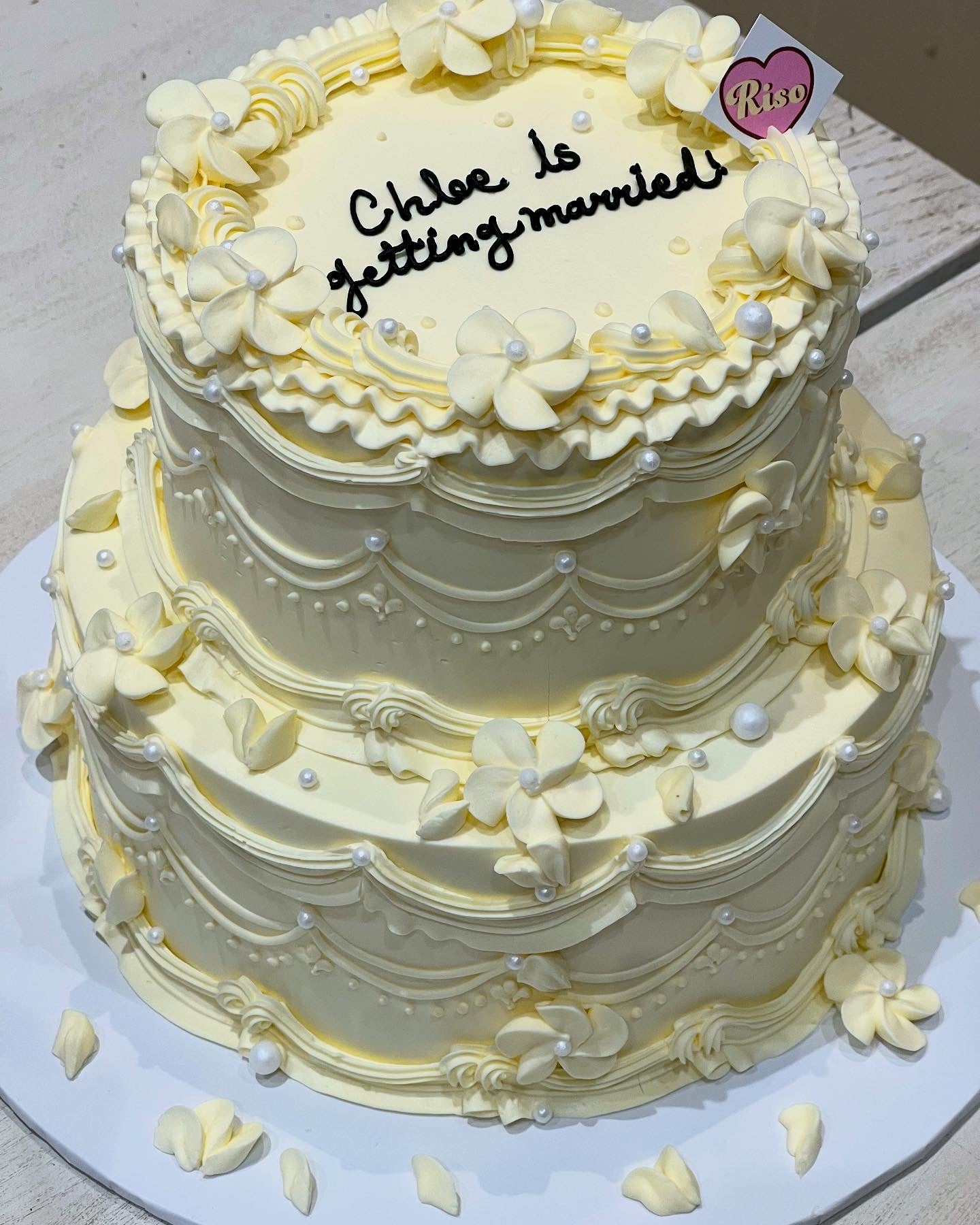 Close-up of piped ruffle edges and cream flower decorations with pearls on a vintage-style wedding cake