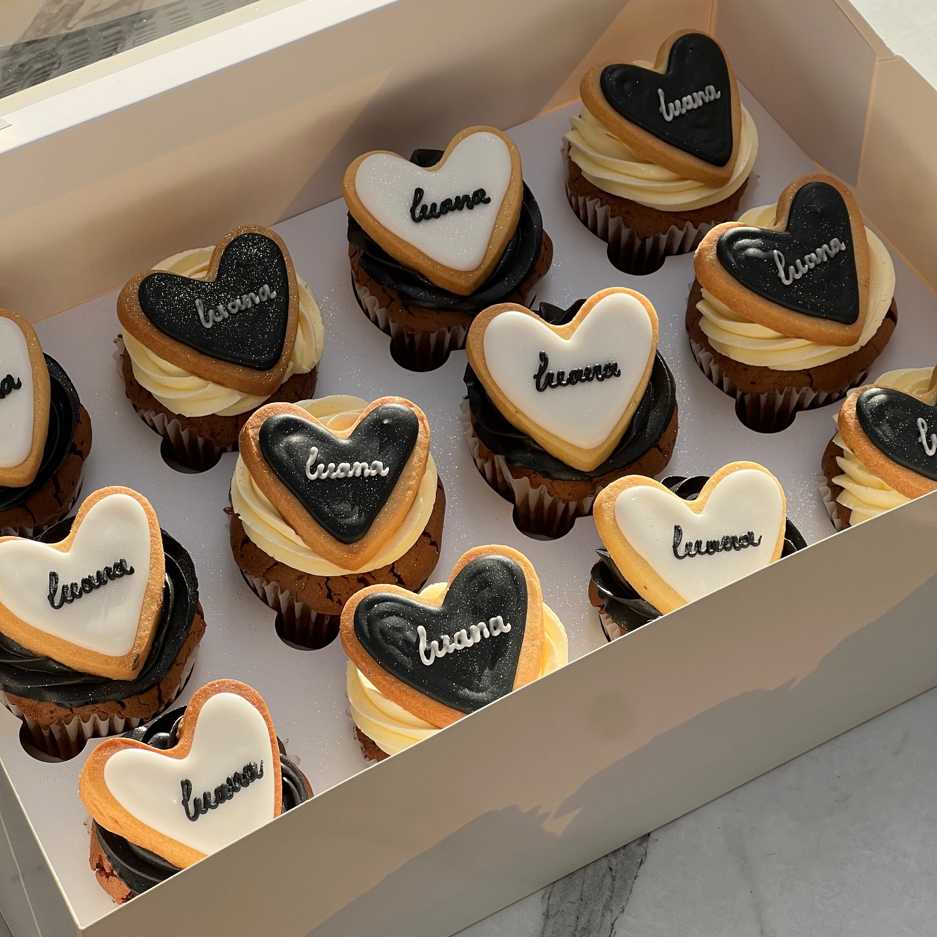 Cupcakes topped with double heart cookies and swirls of white and black cream