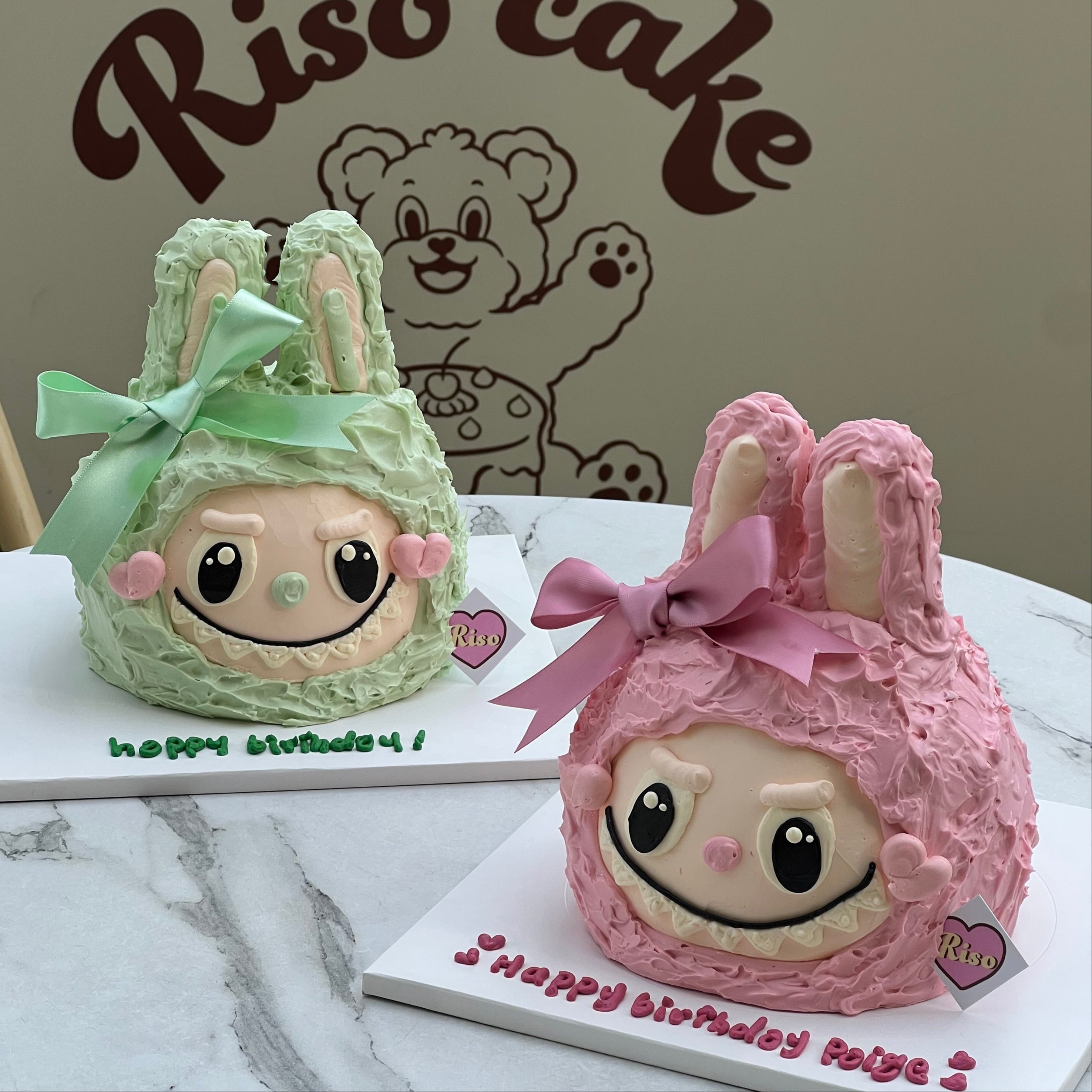 3D Labubu character cakes in pastel green and pink with realistic bunny ears and hand-piped faces, perfect for custom birthday celebrations