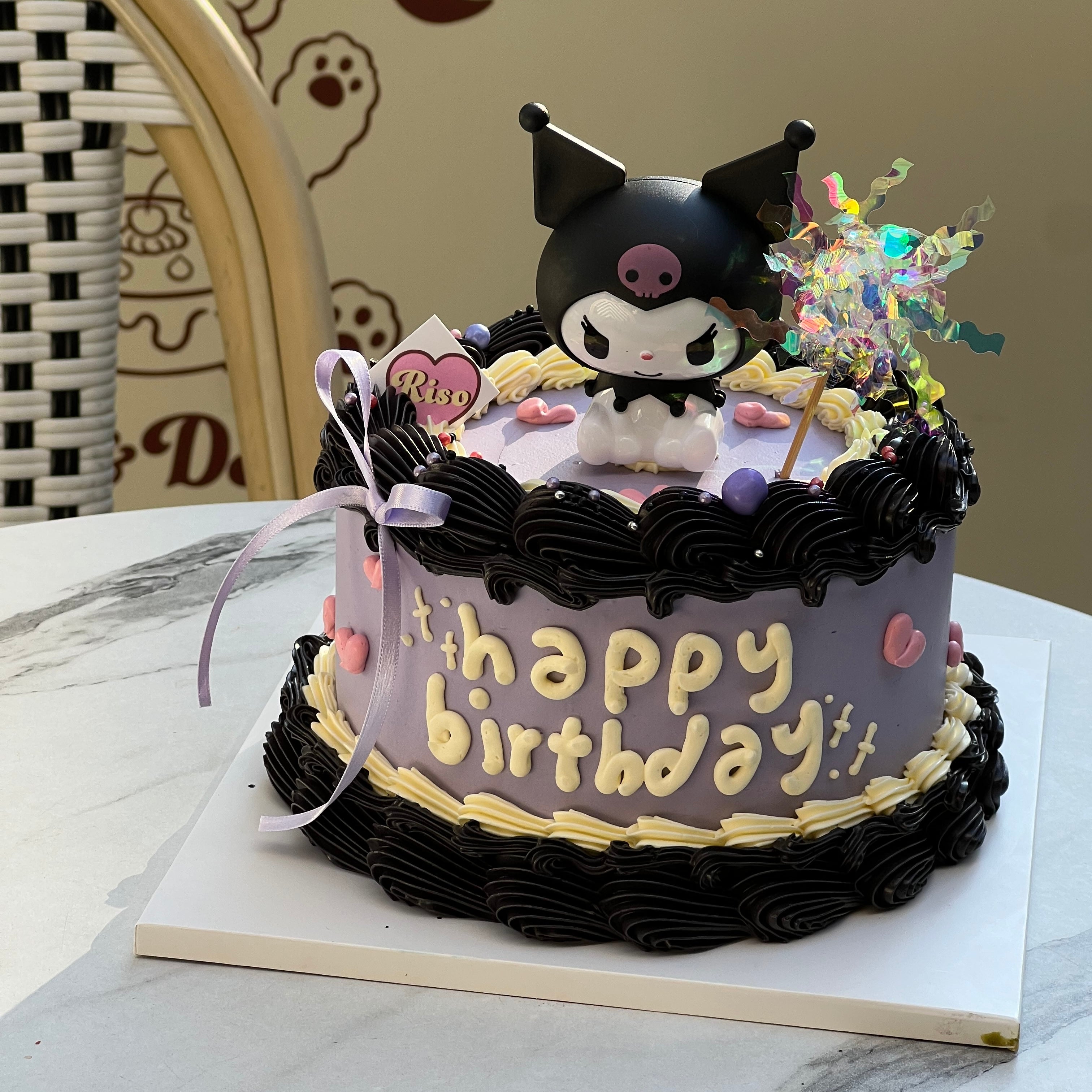 3D Kuromi character cake with black buttercream border, purple icing, and pastel heart decorations