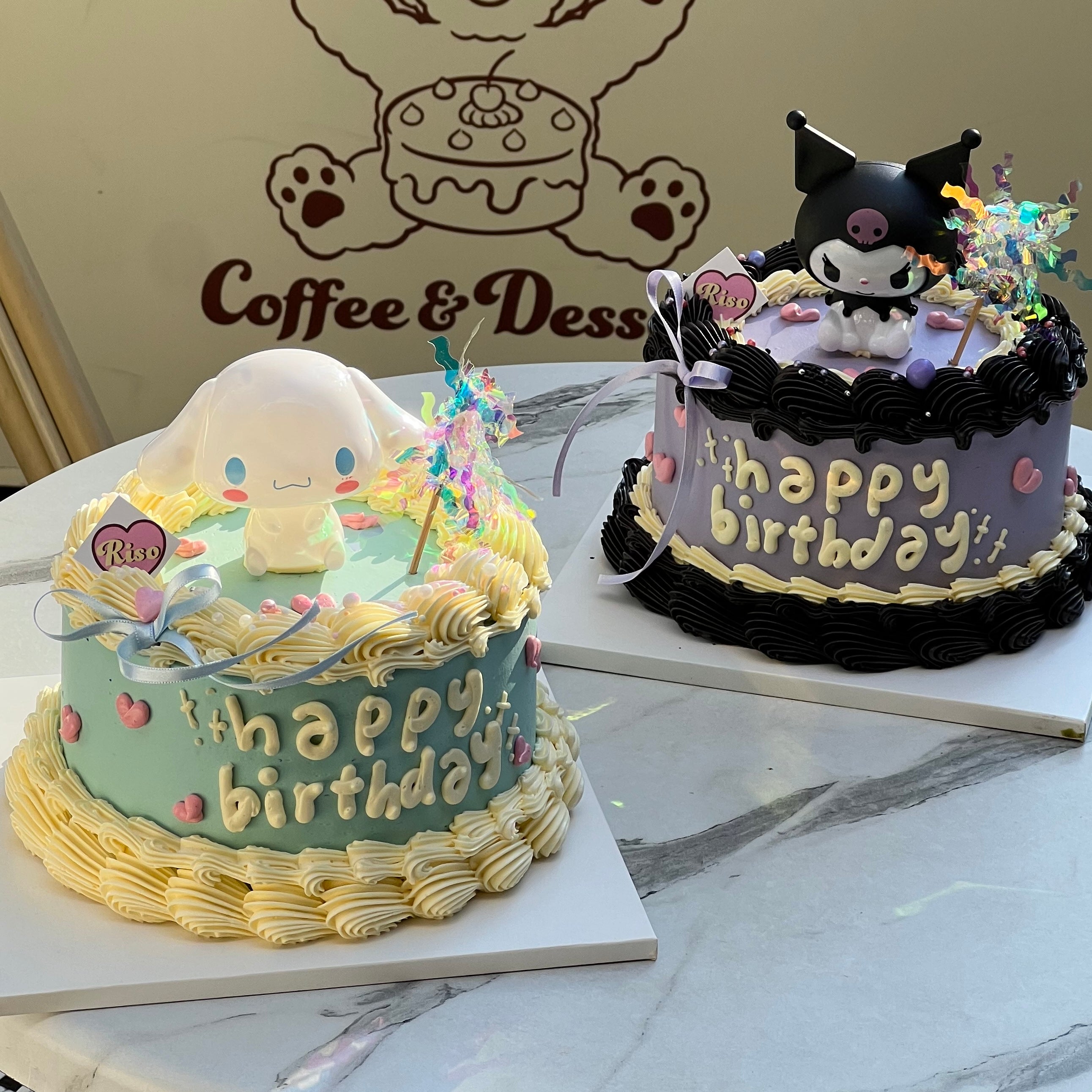 Top-down look at a Kuromi birthday cake with colorful swirl topper, black frosting border, and 3D character in center