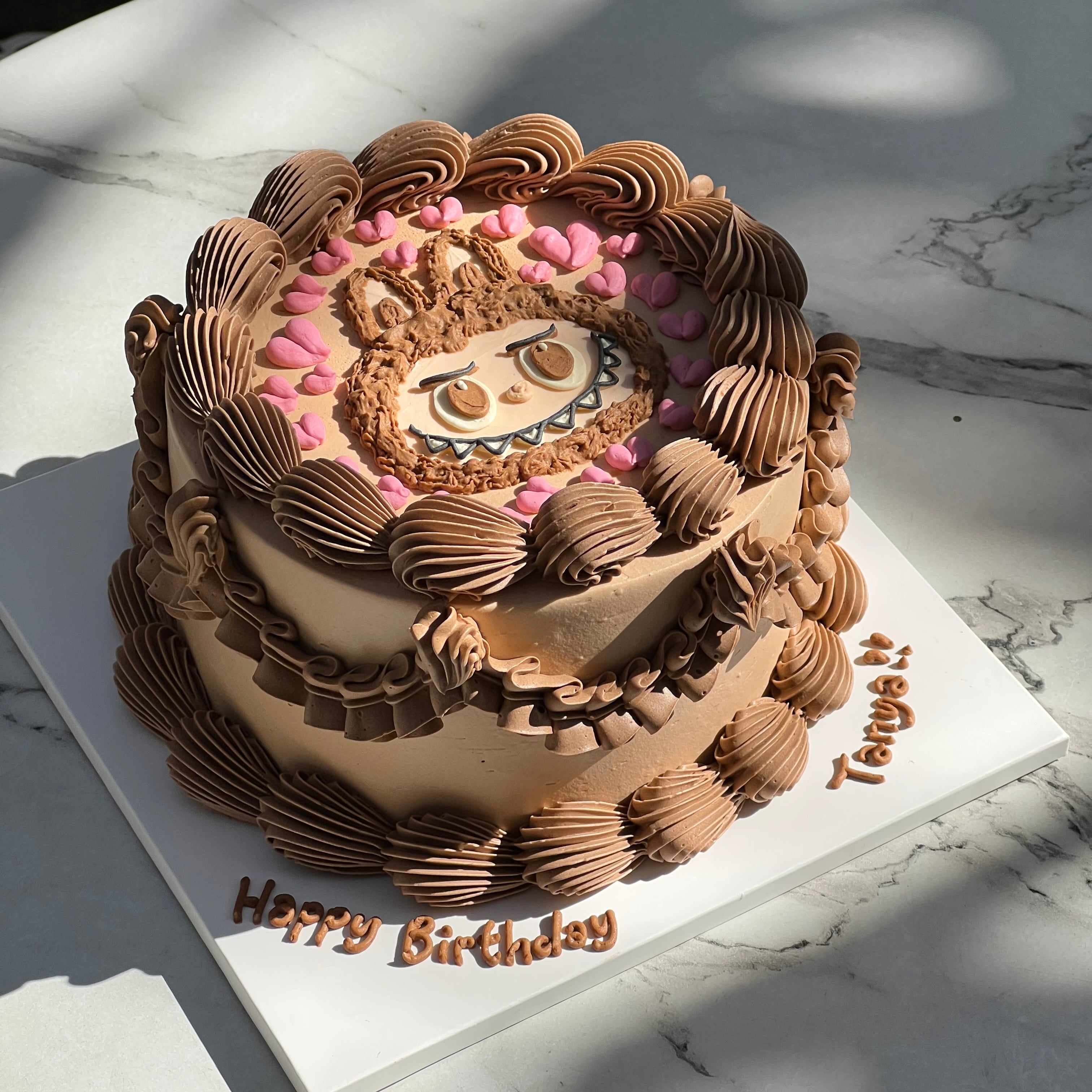 Round Labubu cake with brown cream piping and pink heart accents