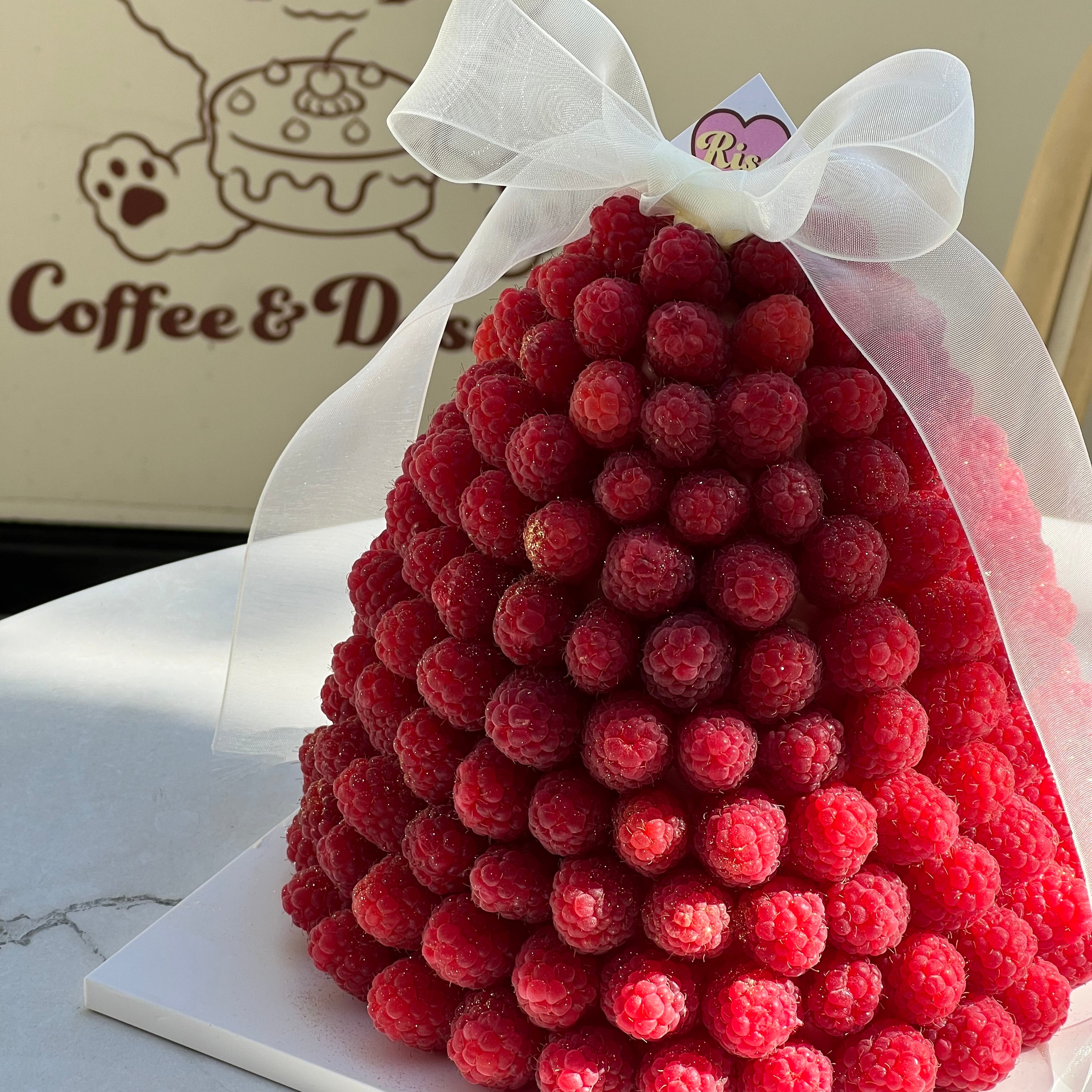 Close-up of a raspberry dome cake, covered in fresh berries with soft natural light