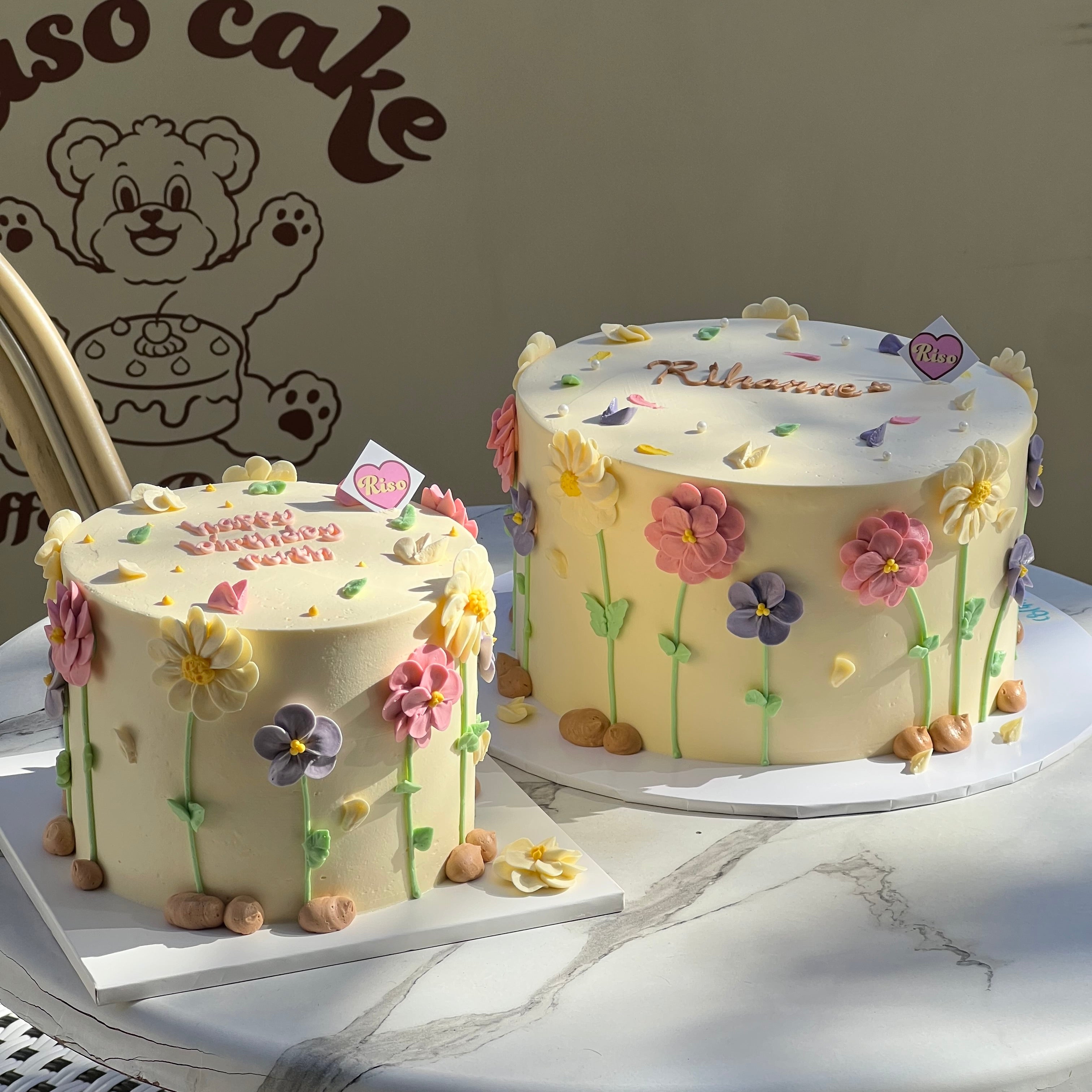 Round floral cake decorated with mixed color daisies and pastel petals