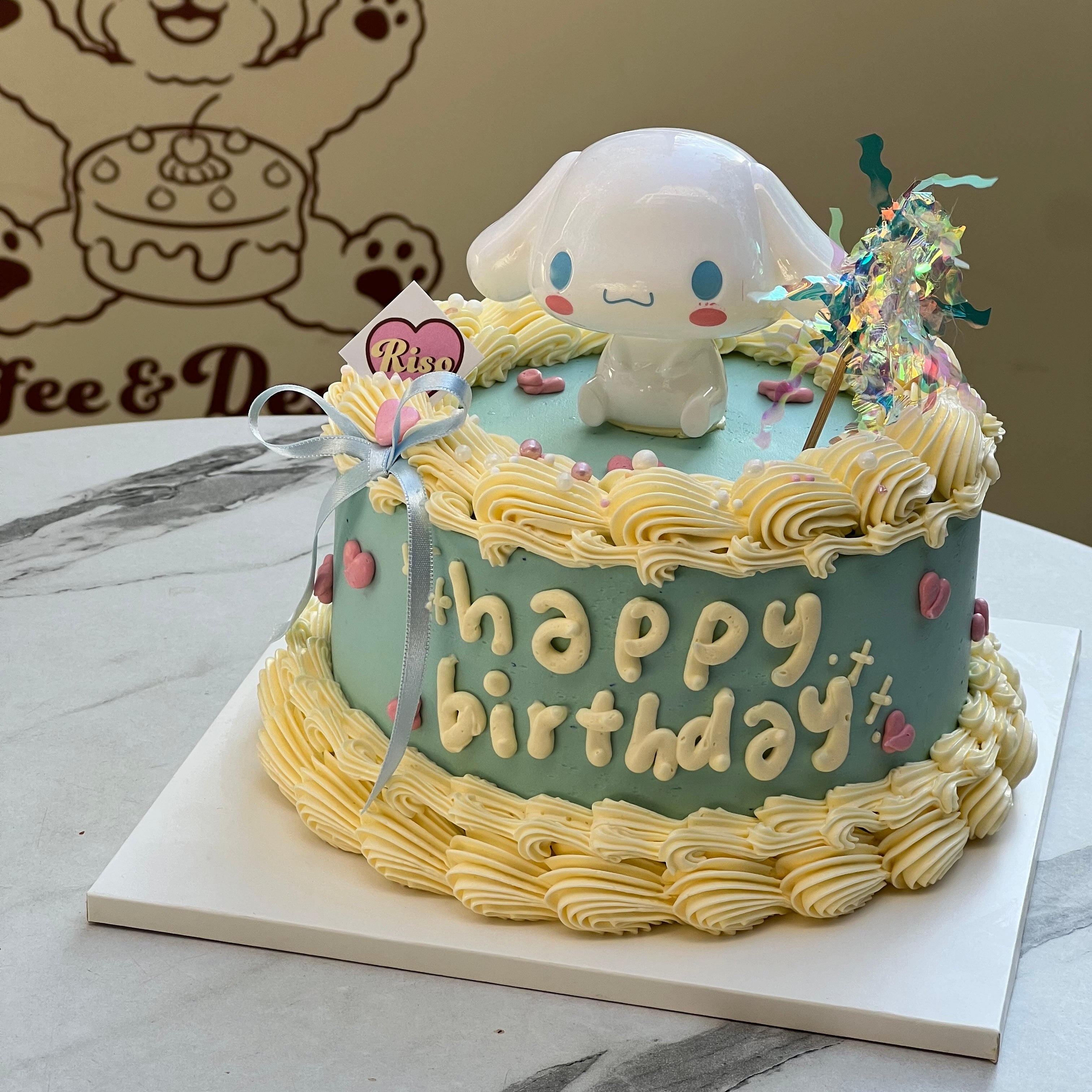 Cinnamoroll-themed birthday cake with 3D topper, blue and yellow buttercream piping, and cute heart accents — perfect for Sanrio fans