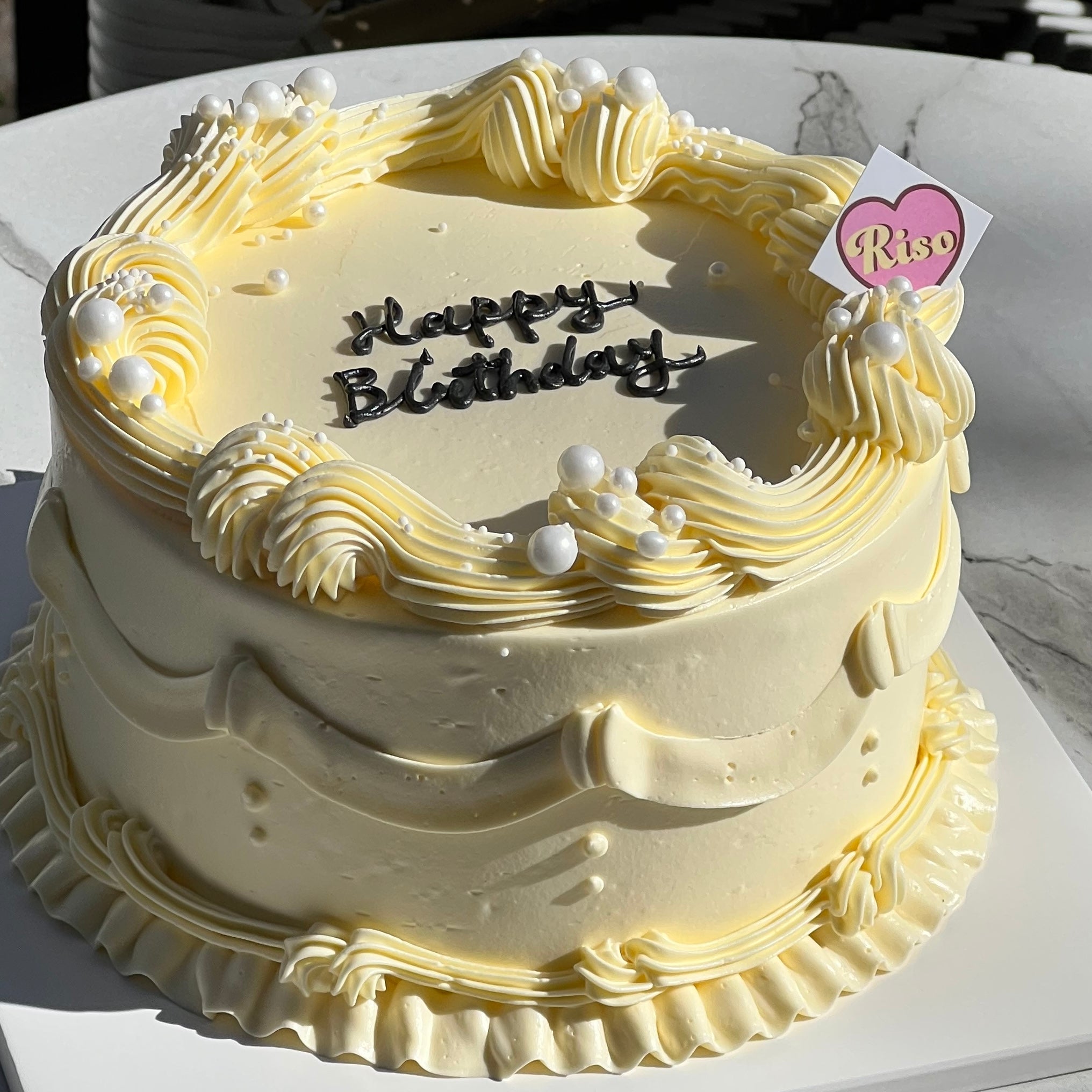 Close-up of piped cream detail and edible pearl decorations on birthday cake