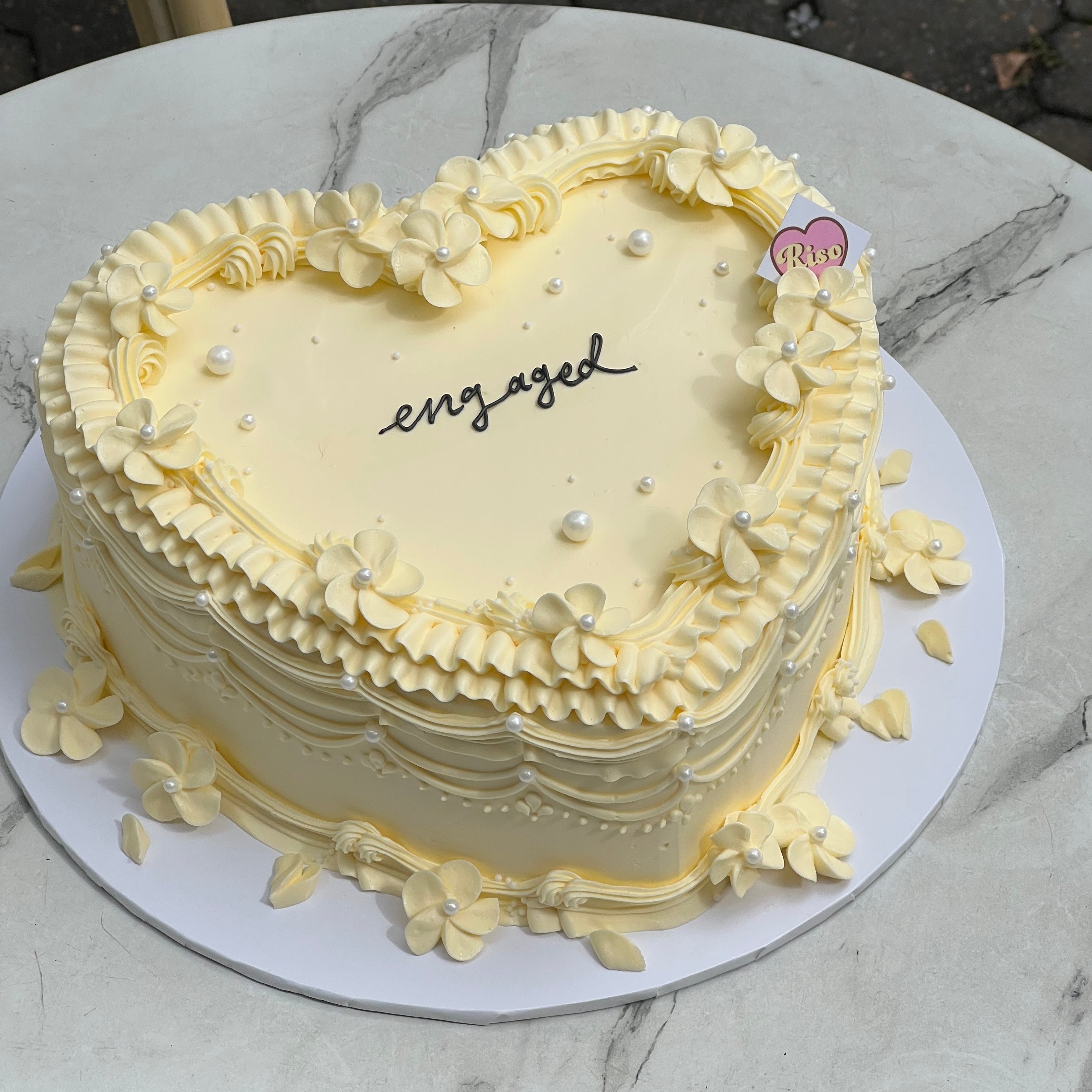 Soft cream-toned celebration cake with delicate floral piping and romantic charm 💍🌸