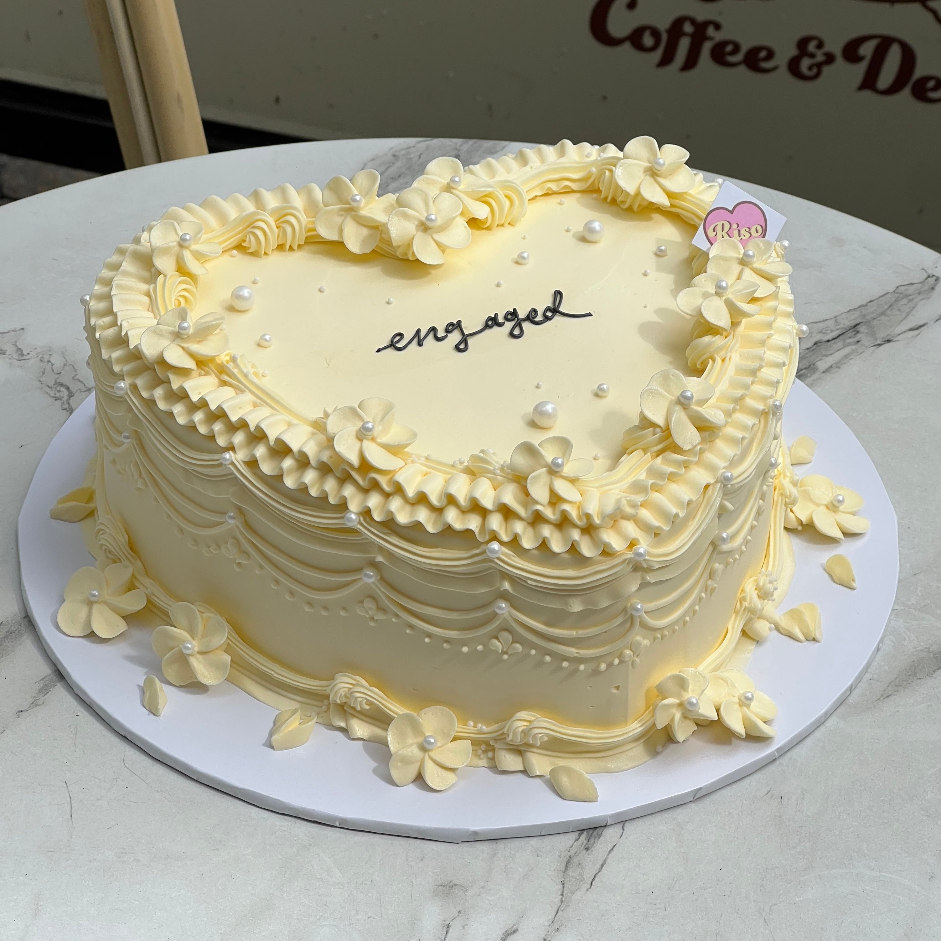 Cream-colored heart-shaped cake with piped flowers and pearls