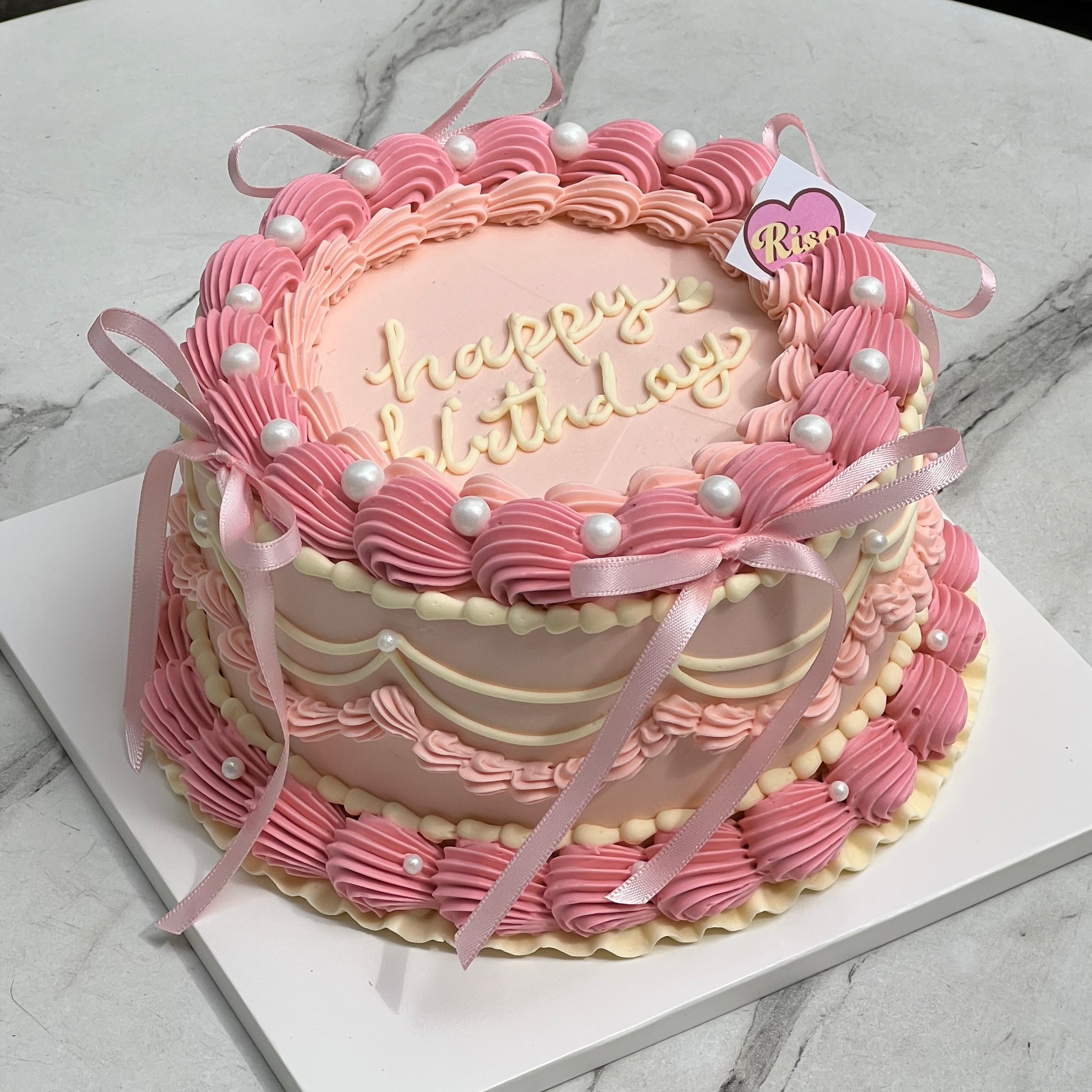 Balletcore aesthetic birthday cake with pink piped icing, satin bows, and edible pearls