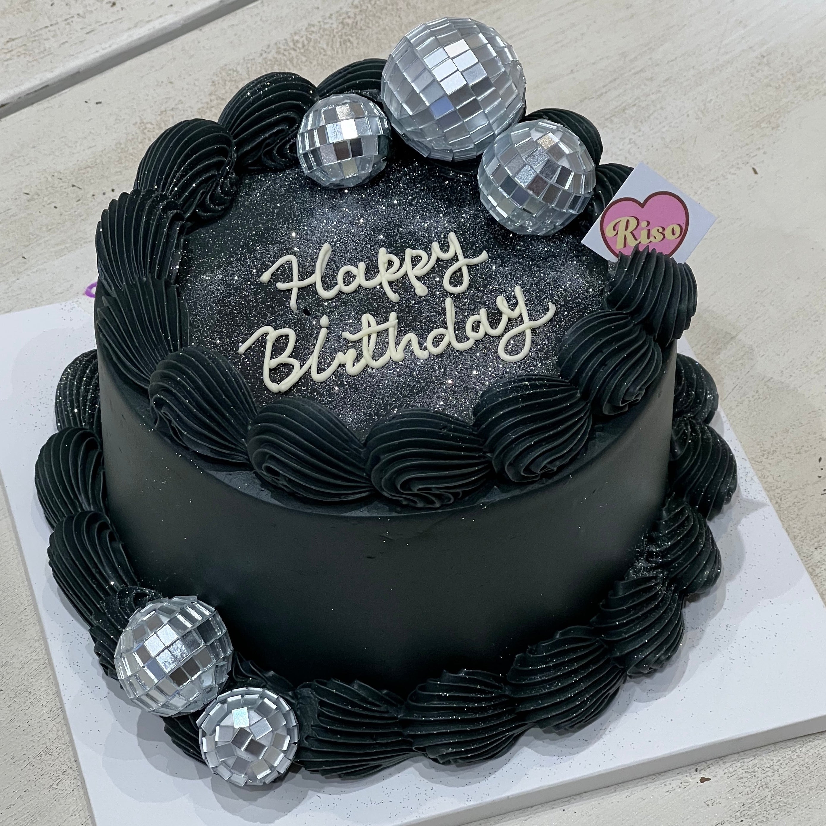Black buttercream cake with “Happy Birthday” text and disco ball toppers