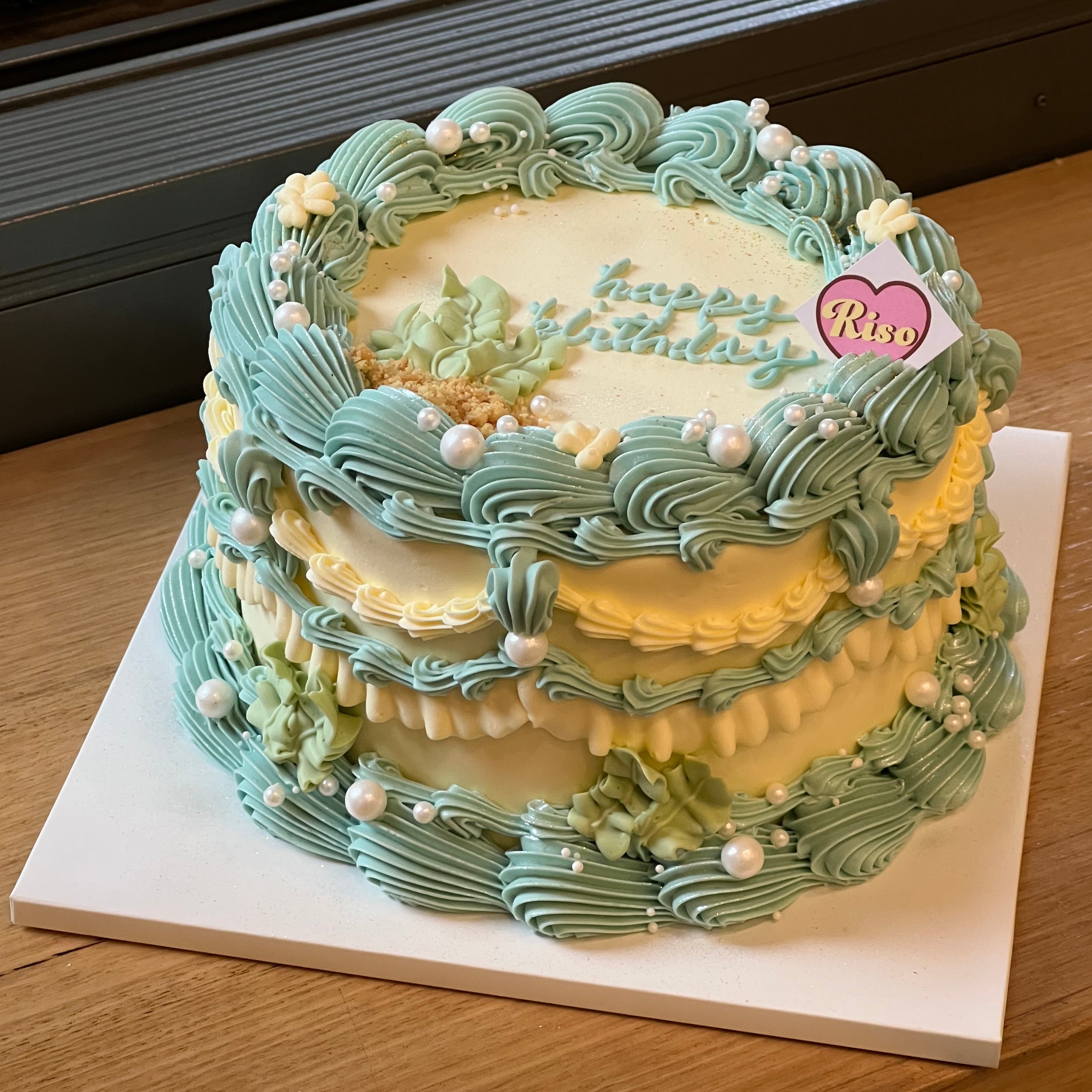 Vintage ocean-themed birthday cake with seashell-like piping, pearls, and marine-inspired pastel colors