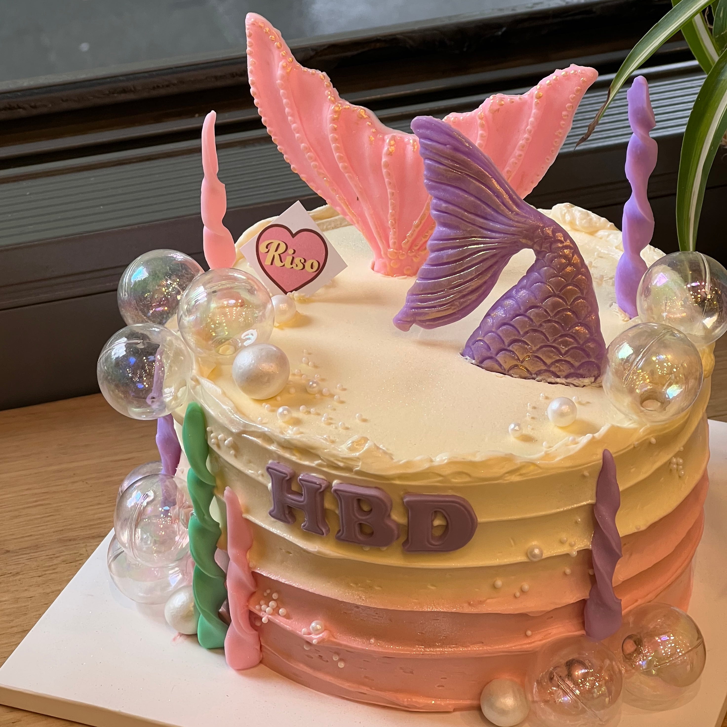 Mermaid-themed birthday cake with two mermaid tails and bubble decorations