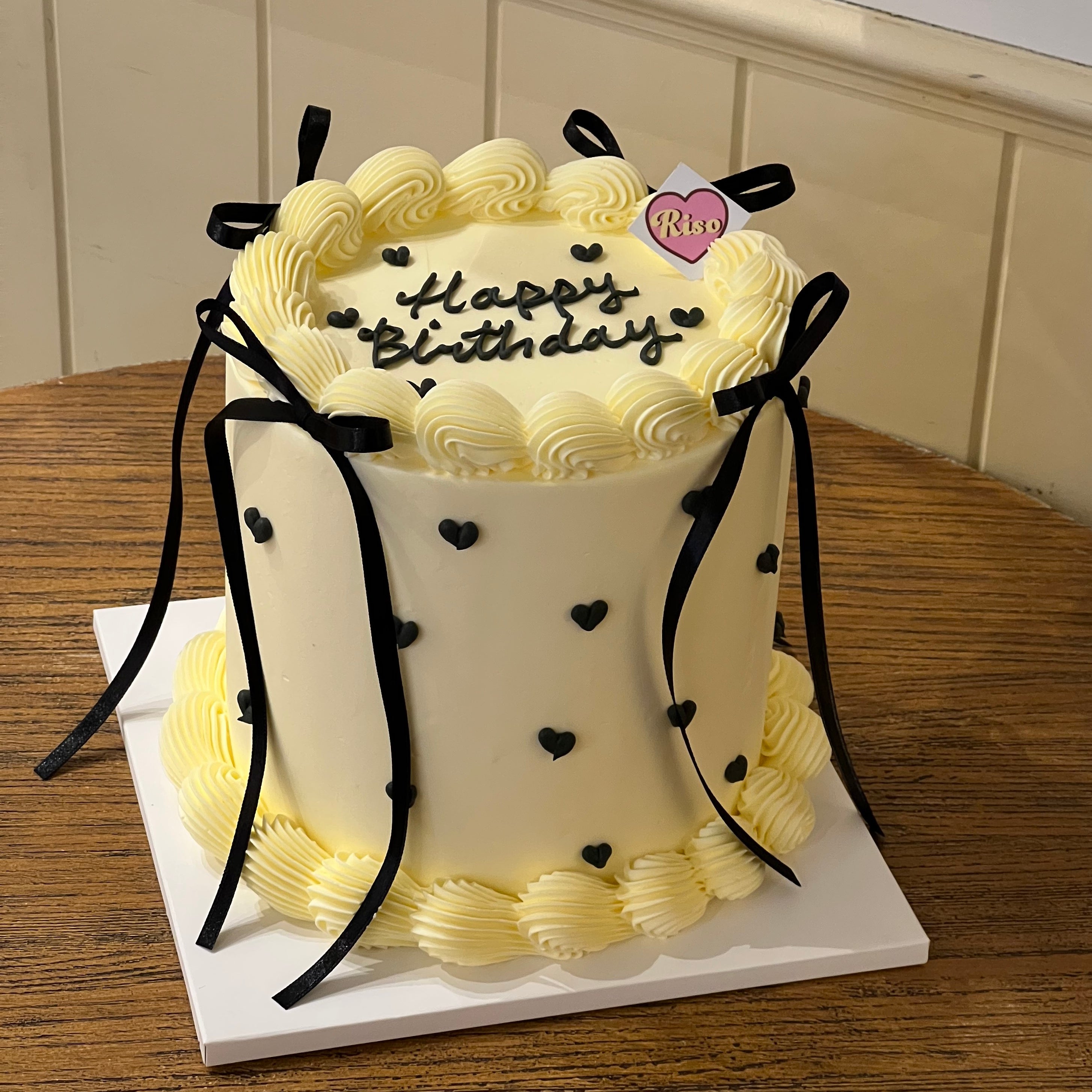 Elegant balletcore-inspired birthday cake with piped black hearts and silky ribbon details