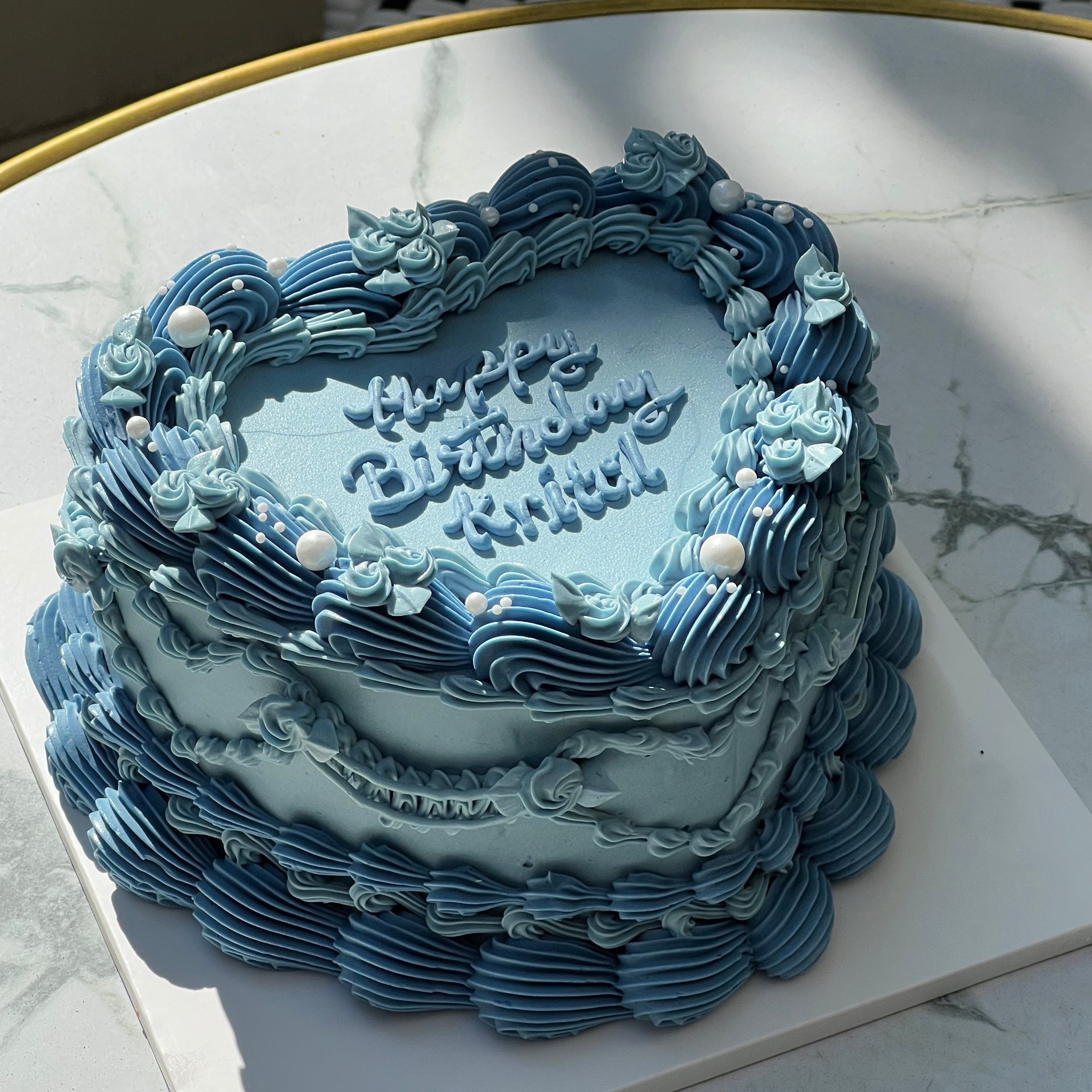 A dreamy, retro-inspired blue cake covered in rosette piping and pearls, capturing the charm of vintage celebration aesthetics