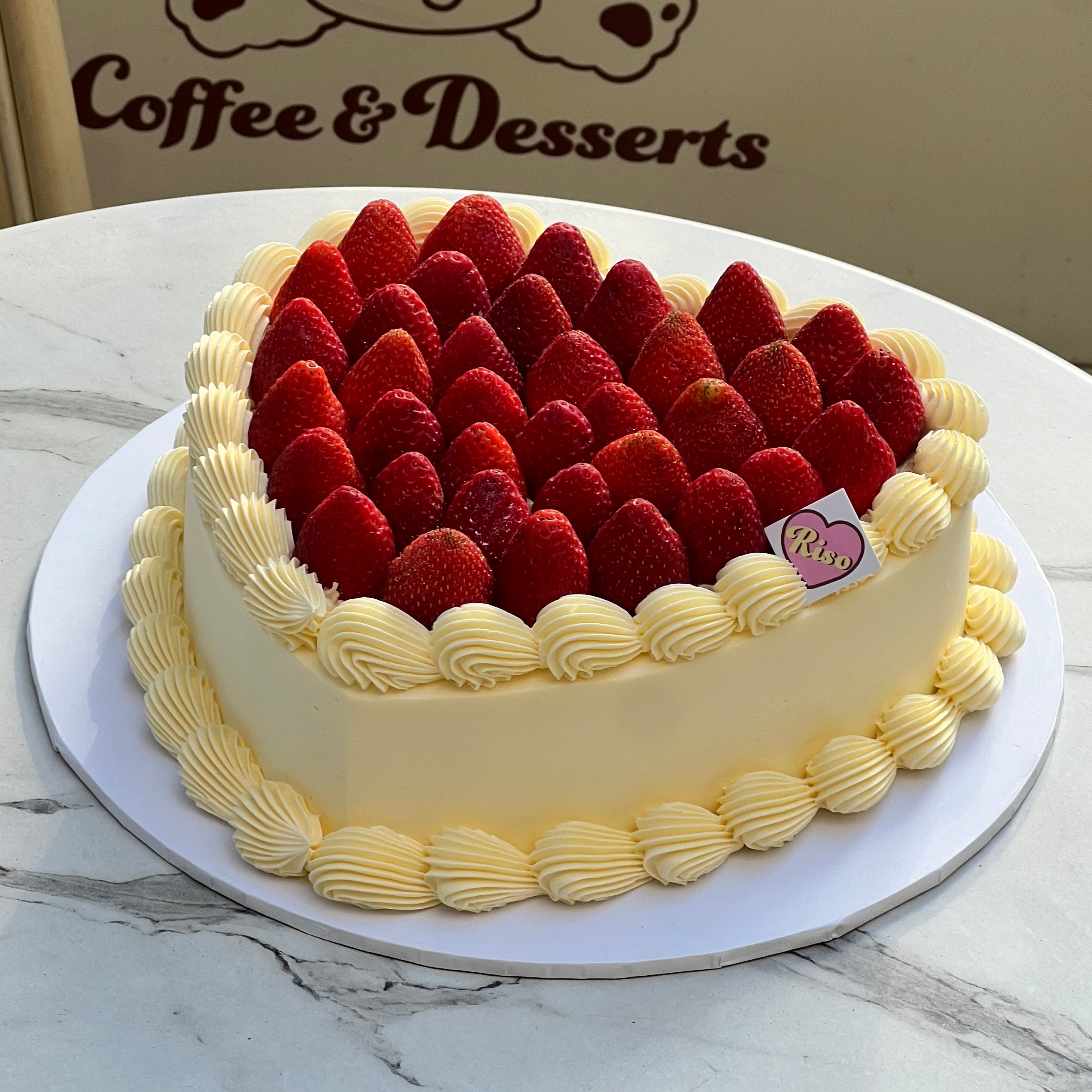 Large heart-shaped strawberry cake with whipped cream borders, perfect for birthdays, anniversaries, and special celebrations