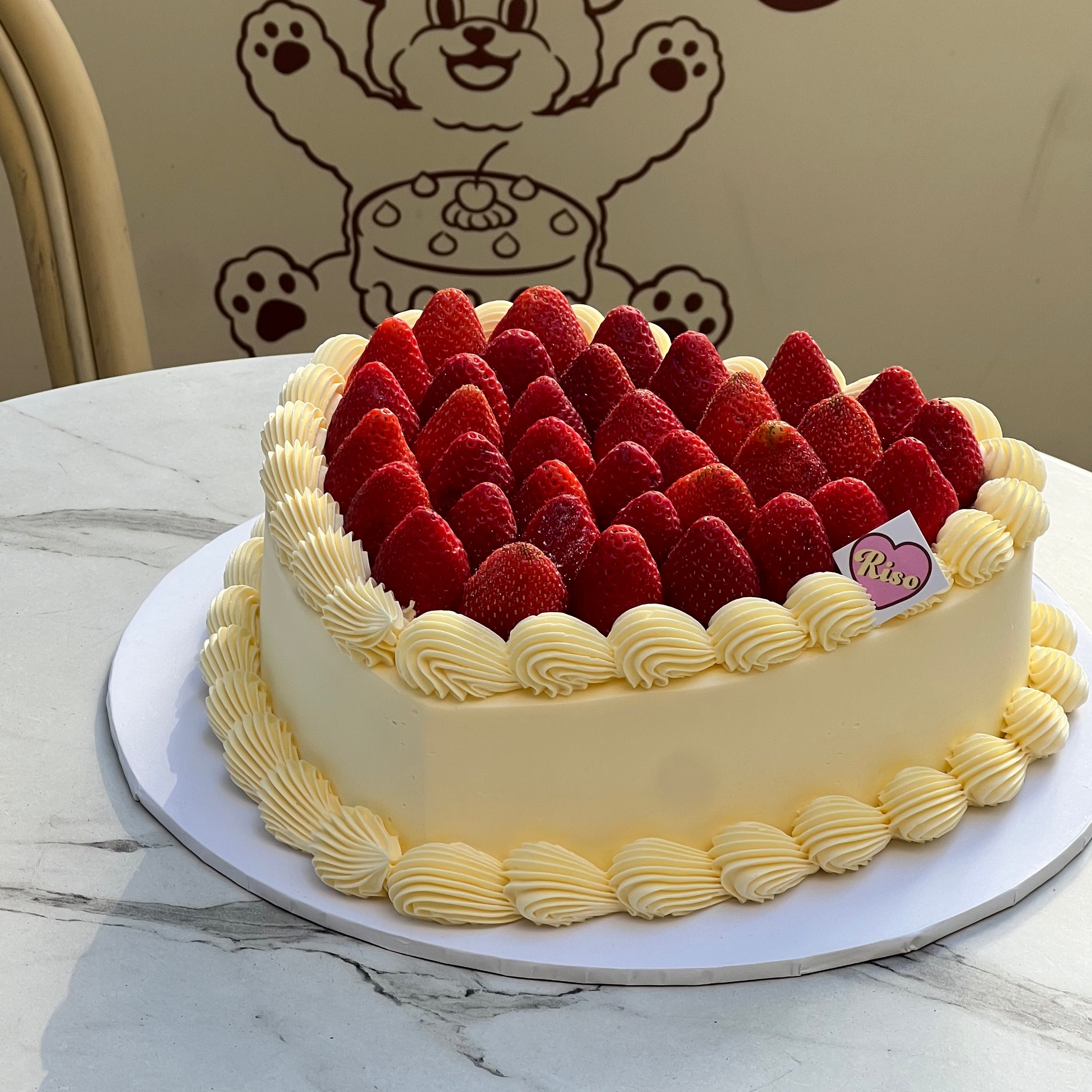 A charming heart cake crowned with a mountain of strawberries and surrounded by soft, creamy swirls — made for party moments