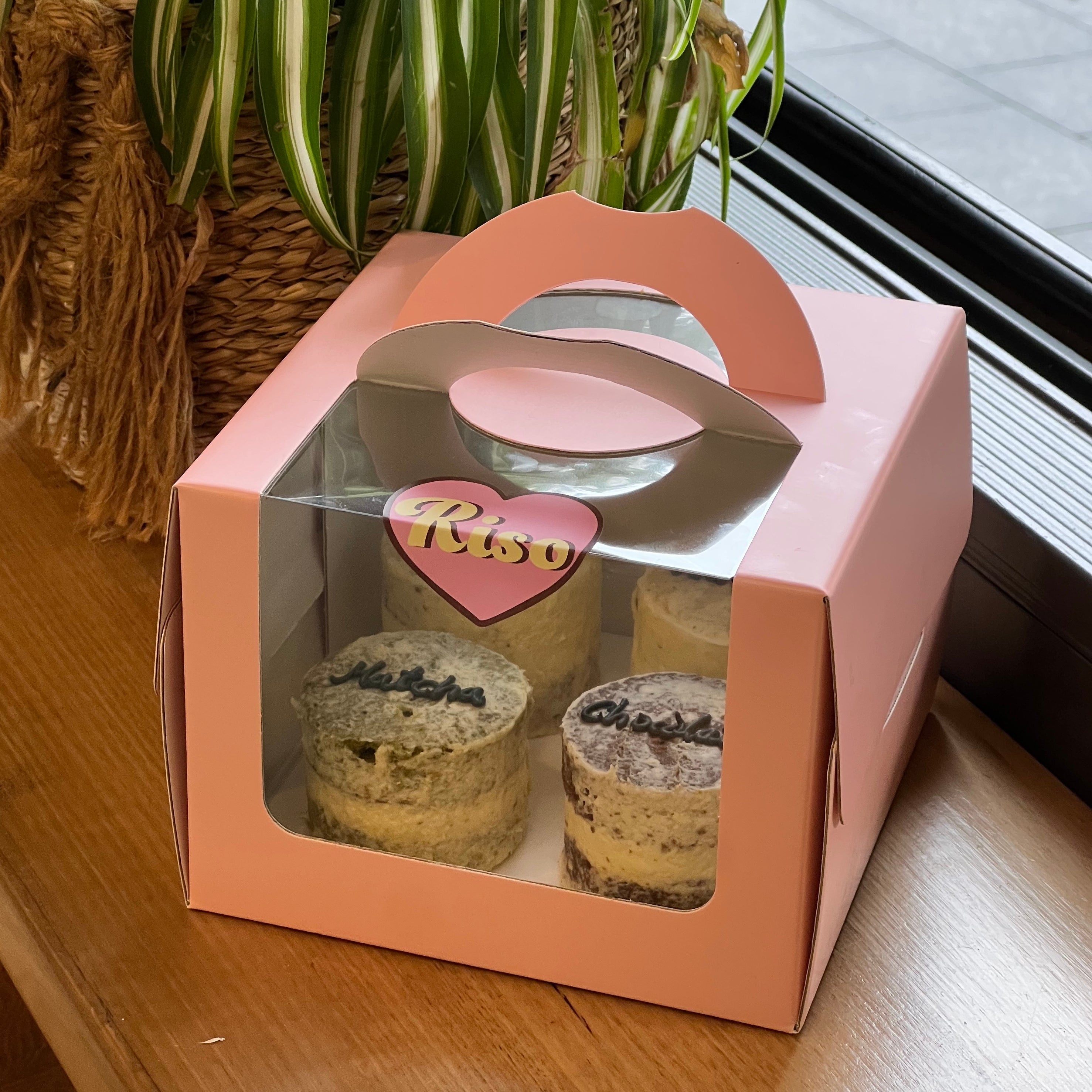Cute and cozy cake sampler box with four rustic-style mini cakes and a pastel pink carry box, perfect for flavor testing or gifting