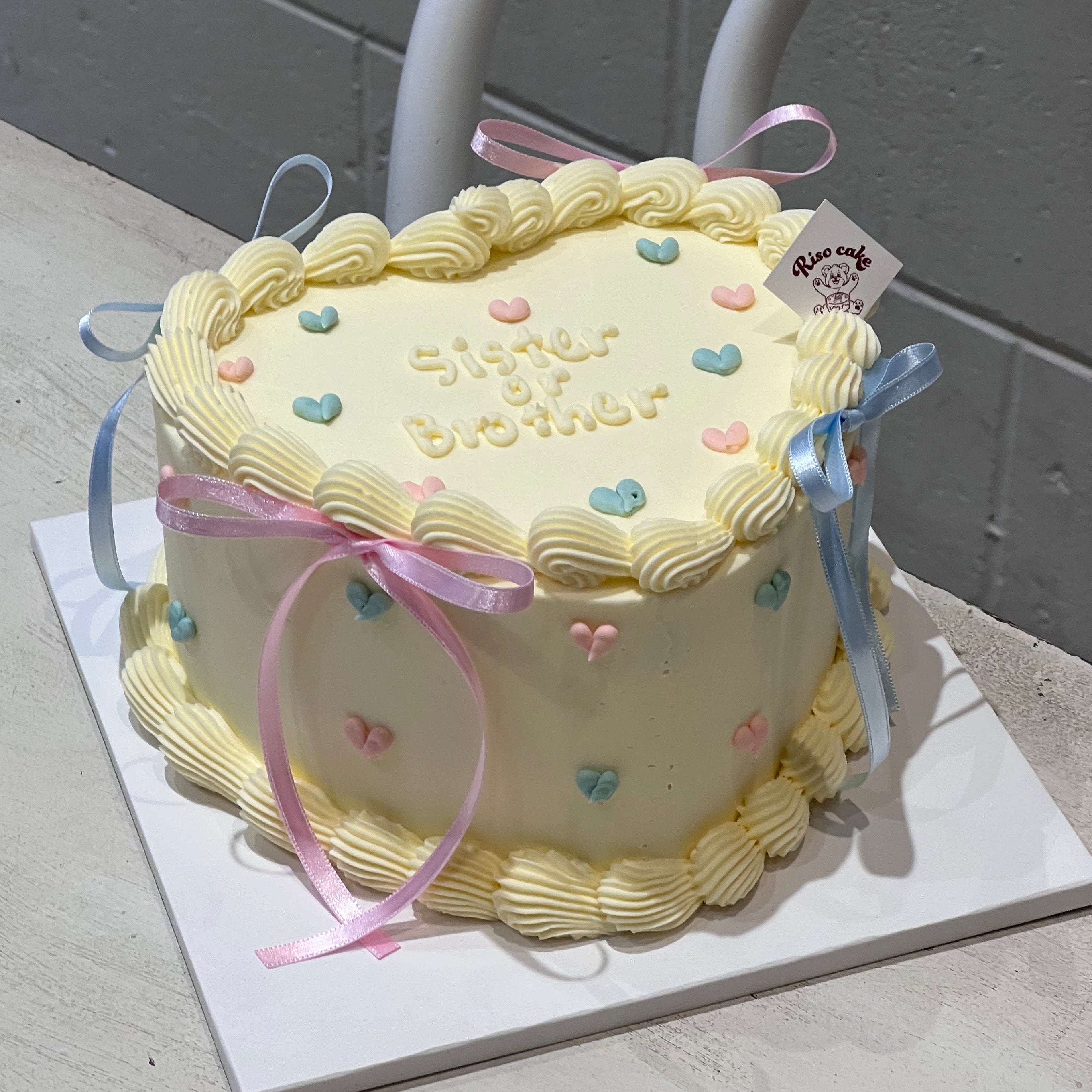 Gender reveal cake in balletcore style, featuring buttercream piping, heart decorations, and pink & blue ribbons for baby shower celebrations