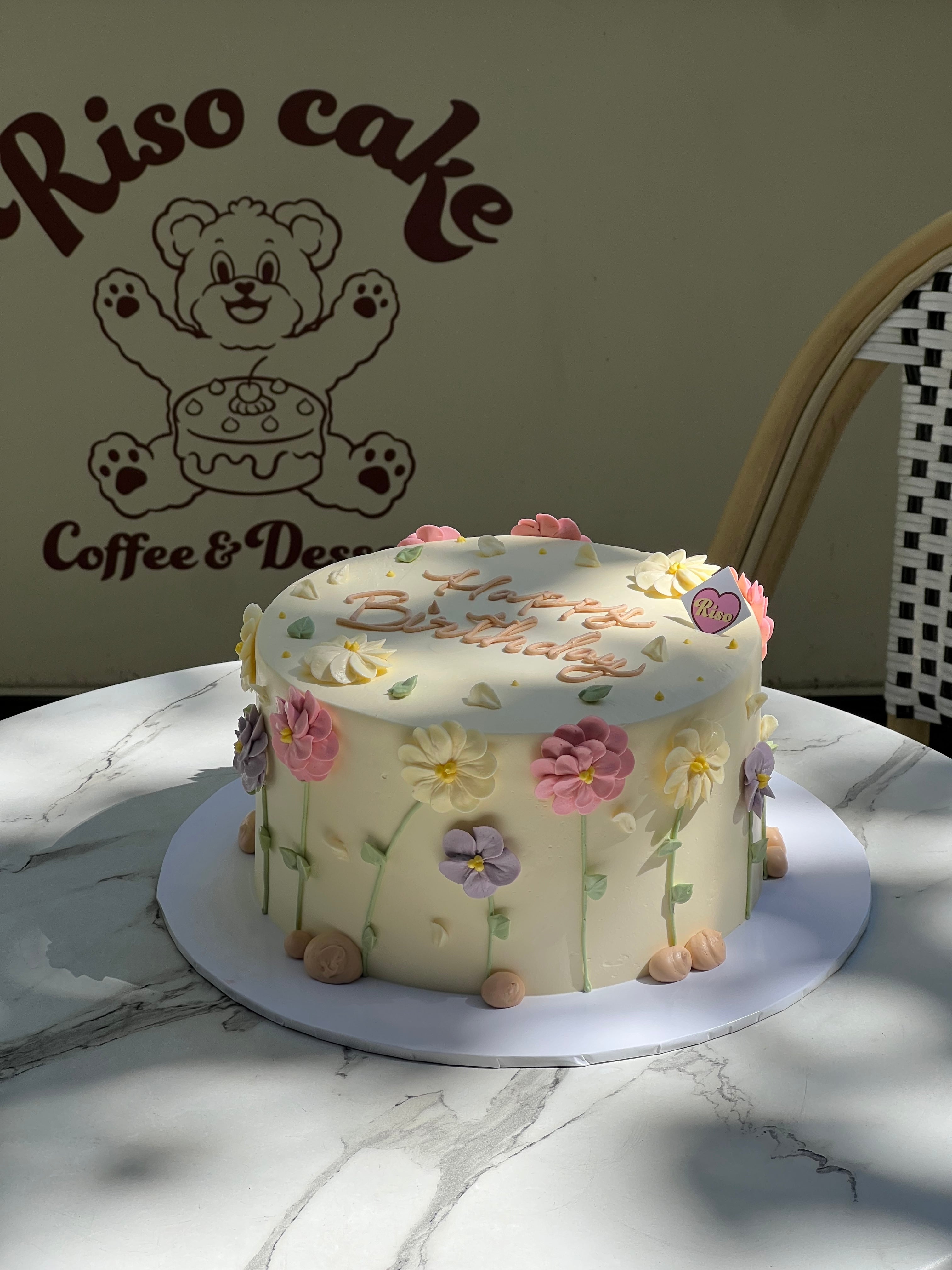 Buttercream cake with colorful daisy flowers in pink, purple, and yellow