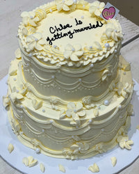 Close-up of piped ruffle edges and cream flower decorations with pearls on a vintage-style wedding cake