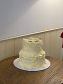 Elegant bridal-themed vintage cake with delicate cream florals, pearl details, and romantic piping