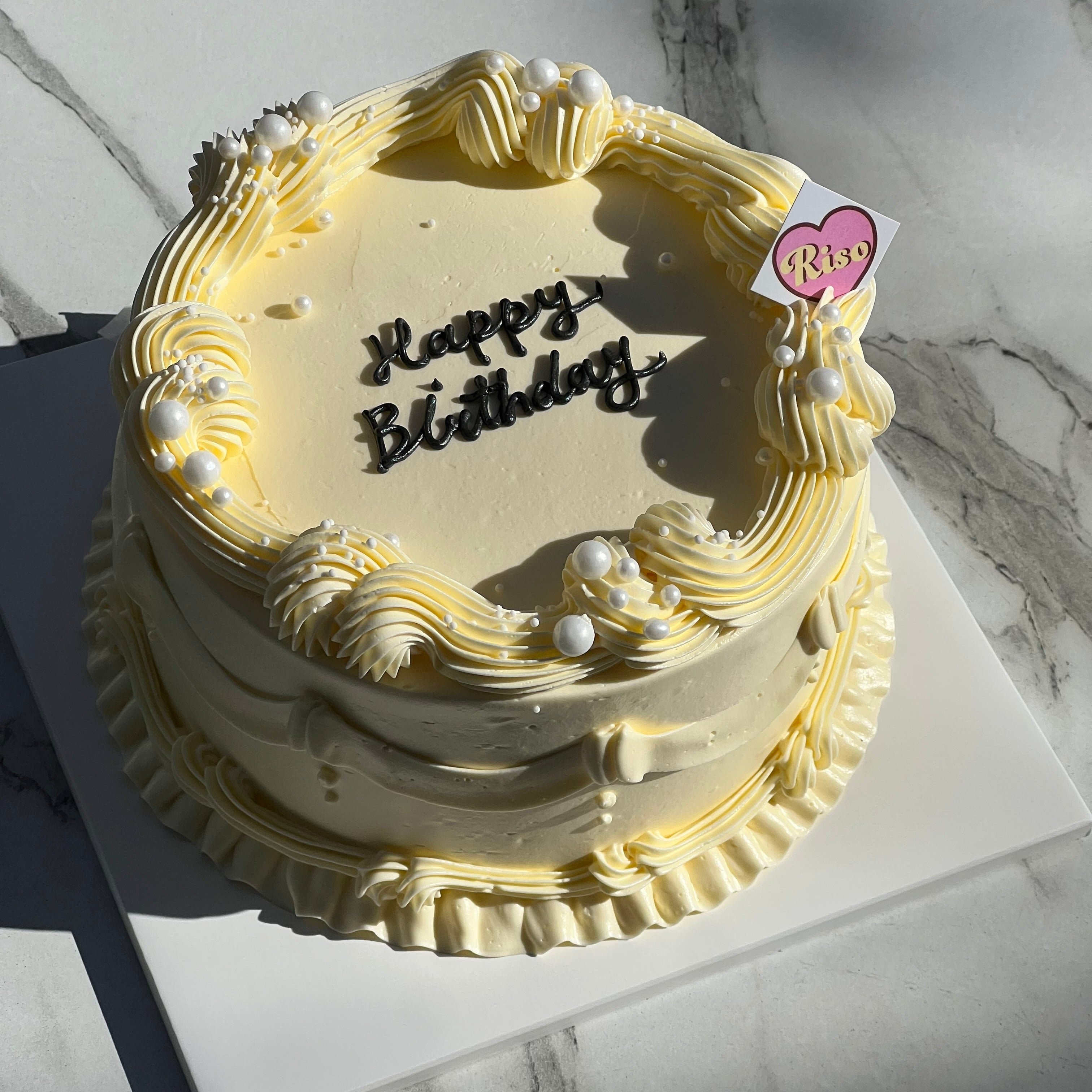 Top view of vintage cream birthday cake with piped border and pearl accents