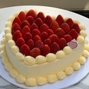 Close-up of the cake’s edge showing delicate whipped cream piping and glossy strawberries arranged in a neat heart pattern