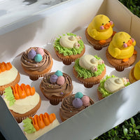 Cute Easter cupcakes featuring yellow chick toppers, bunny tails in green grass frosting, carrot designs, and pastel chocolate egg decorations — perfect for Easter parties or spring gatherings